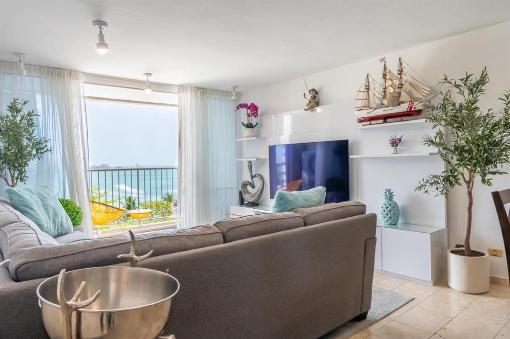 A living room features a grey sofa, a wall-mounted television, and a balcony overlooking the ocean — 6165 AV, ISLA VERDE UNIT 669, CAROLINA, PR