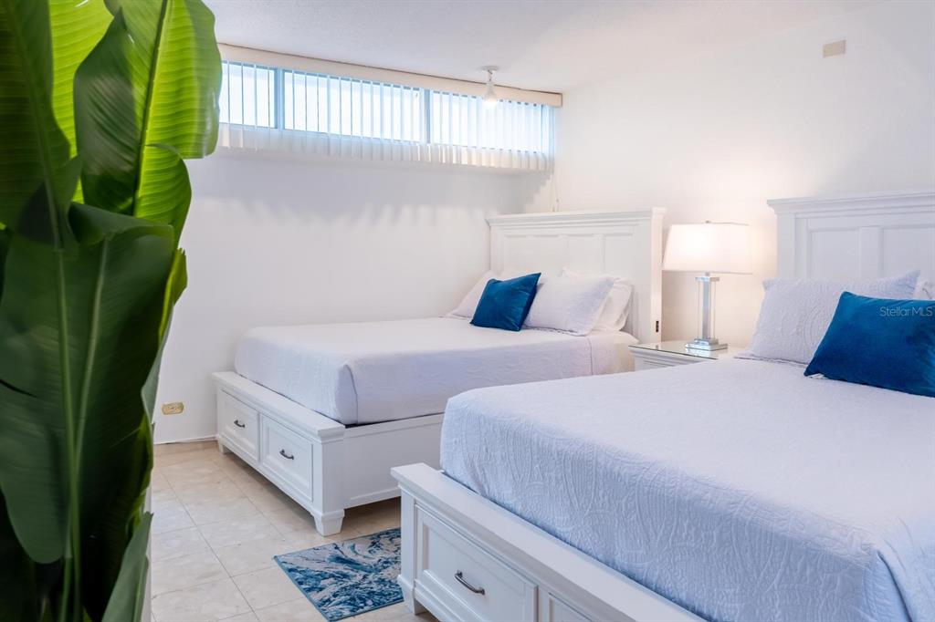 A bedroom features two white storage beds with blue pillows and a large potted plant — 6165 AV, ISLA VERDE UNIT 669, CAROLINA, PR
