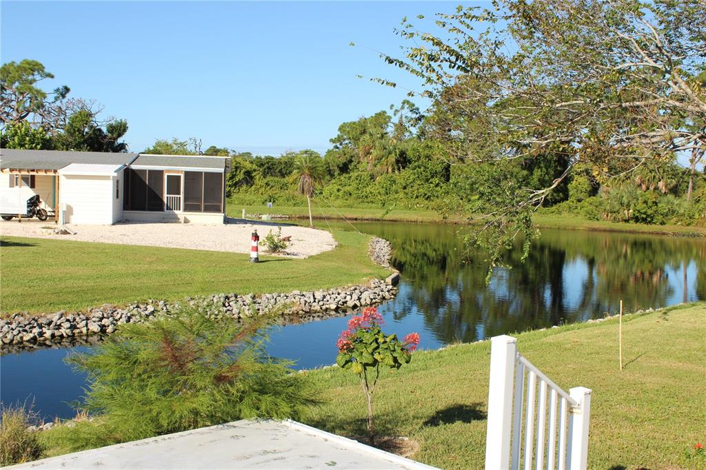 A view of a pond and a neighboring house from a grassy backyard — 3304 CATBIRD LANE, ENGLEWOOD, FL