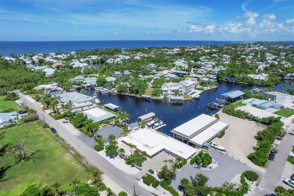 An aerial view shows waterfront homes and boat docks along a canal near the ocean — 161 DAMFICARE STREET, BOCA GRANDE, FL