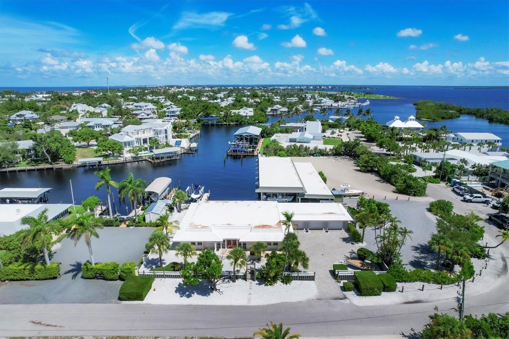 An aerial view of a waterfront property with a white house, boat docks, and palm trees — 161 DAMFICARE STREET, BOCA GRANDE, FL