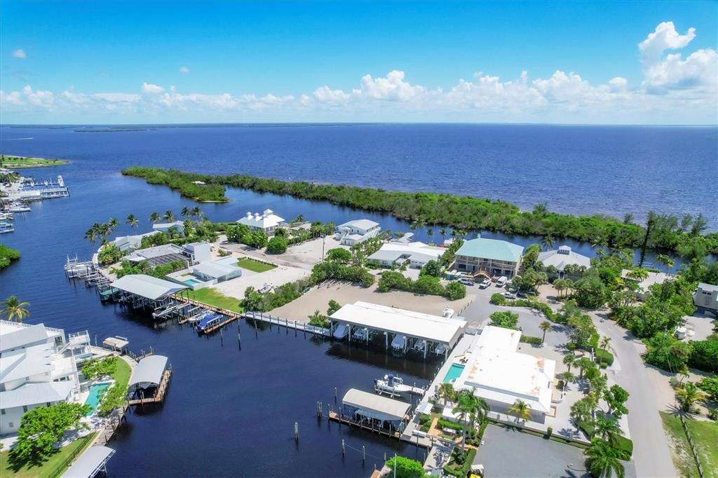 An aerial view shows waterfront homes with private boat docks along a canal and bay — 161 DAMFICARE STREET, BOCA GRANDE, FL