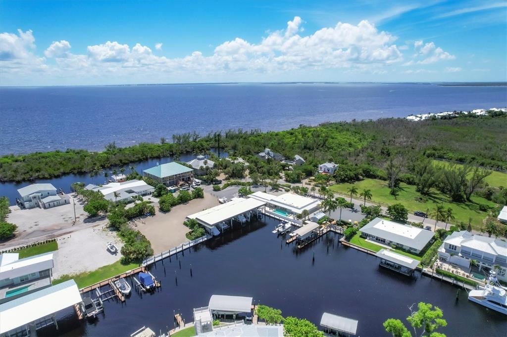 An aerial view shows a waterfront property with boat slips, docks, and several residential buildings — 161 DAMFICARE STREET, BOCA GRANDE, FL