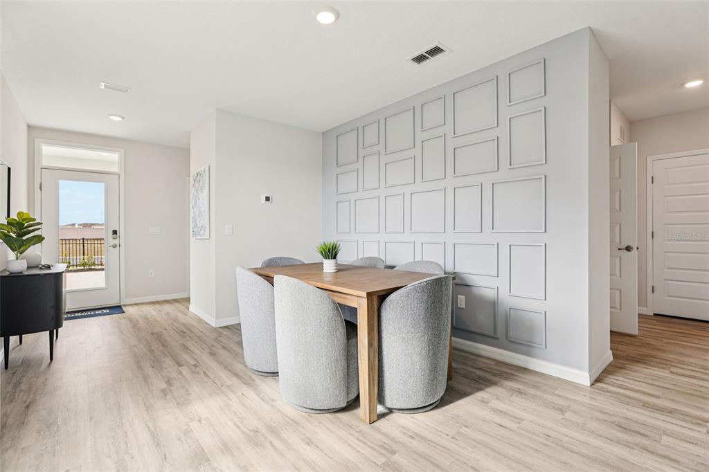 A dining area features a wooden table, gray upholstered chairs, and a paneled accent wall — 4815 KHLOE COURT, WINTER HAVEN, FL