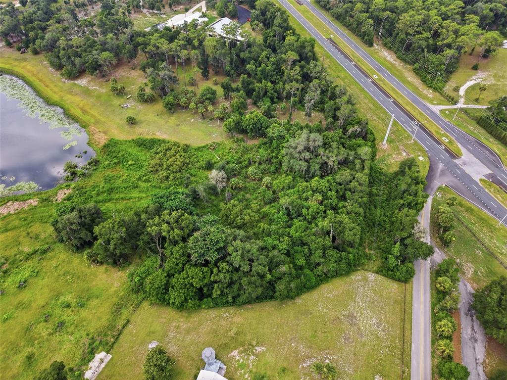 An aerial view shows a wooded lot situated between a pond and a divided highway — 4155 N US HIGHWAY 17, DELAND, FL