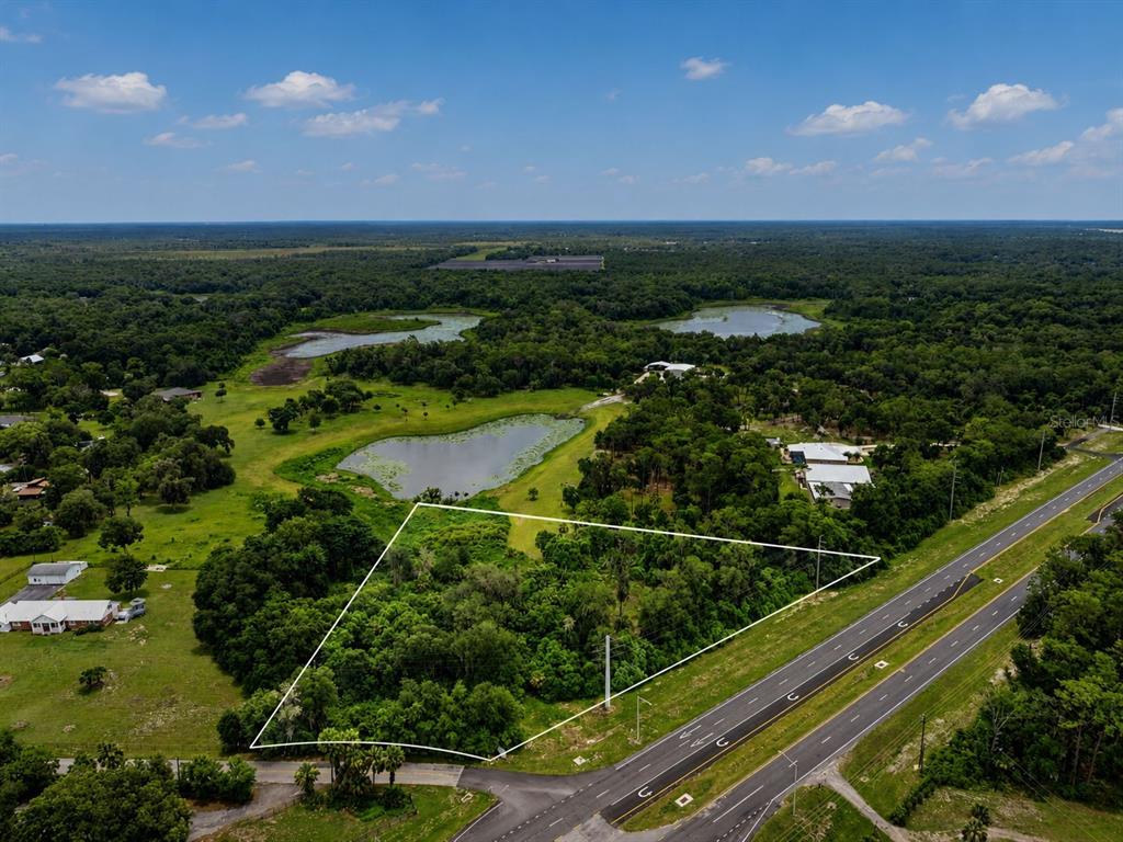 An aerial view shows a wooded, trapezoidal plot of land adjacent to a multi-lane highway — 4155 N US HIGHWAY 17, DELAND, FL