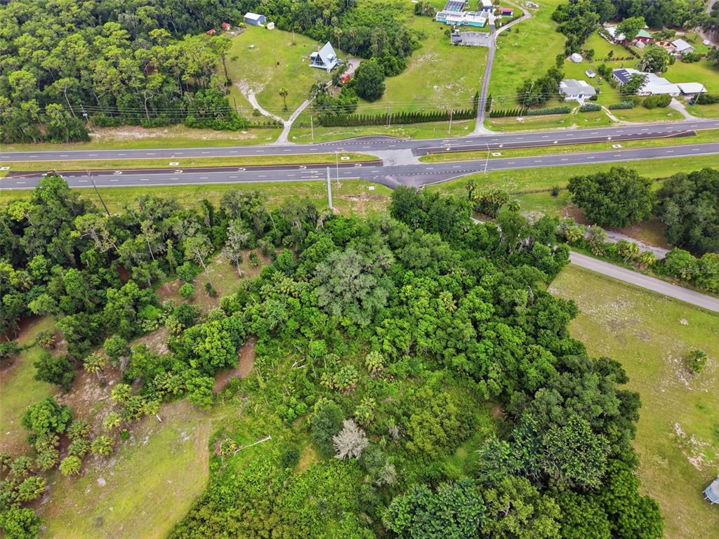 An aerial view shows a wooded lot bordered by a highway and grassy fields — 4155 N US HIGHWAY 17, DELAND, FL