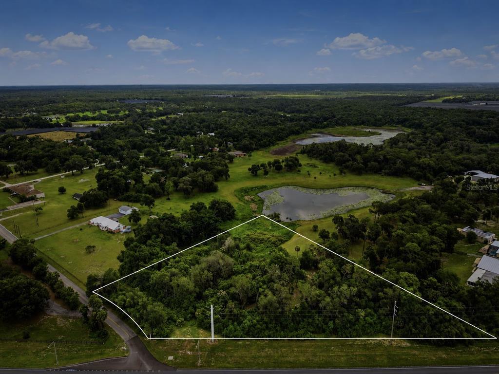 An aerial view shows a wooded, triangular-shaped plot of land bordered by a road — 4155 N US HIGHWAY 17, DELAND, FL