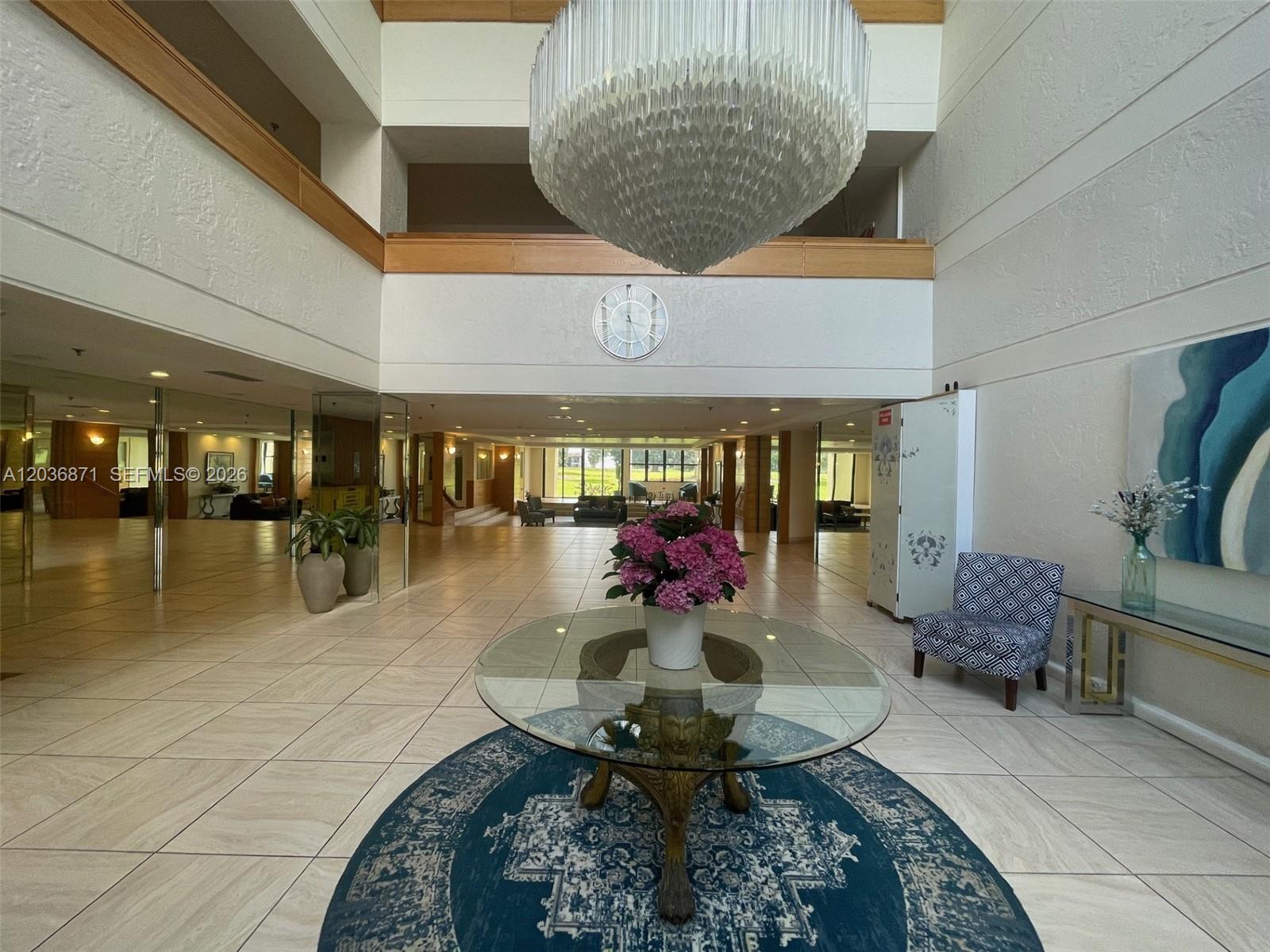 A spacious lobby features a large crystal chandelier, a round glass table, and tiled flooring — 16300 Golf Club Rd # 508, Weston FL 33326, WESTON, FL