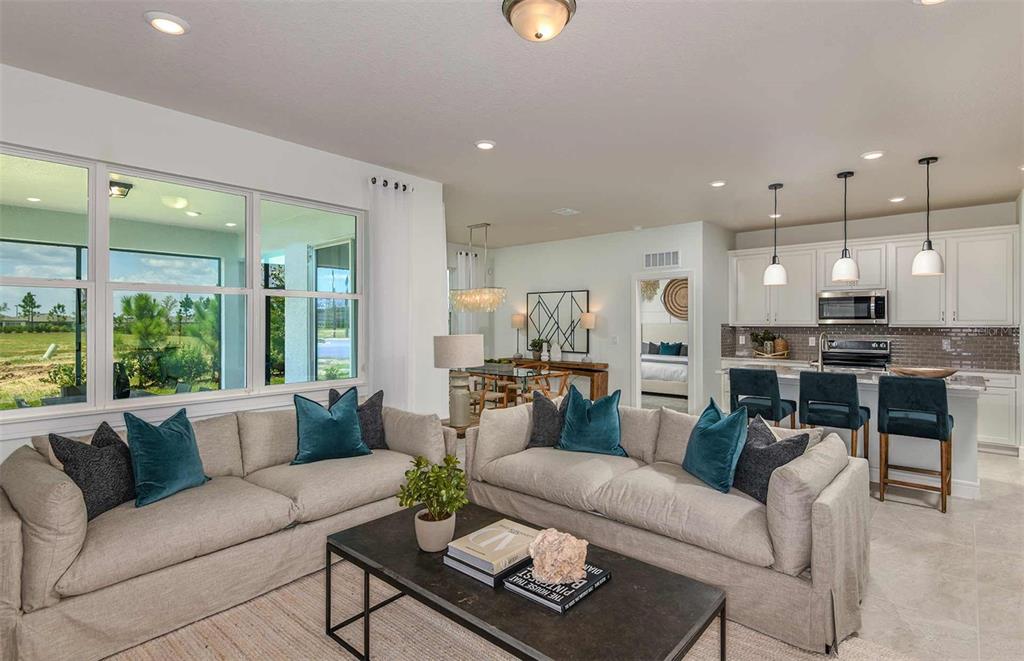 A living room with two beige sofas faces a kitchen with white cabinets and stools — 8557 SW 65TH STREET ROAD, OCALA, FL