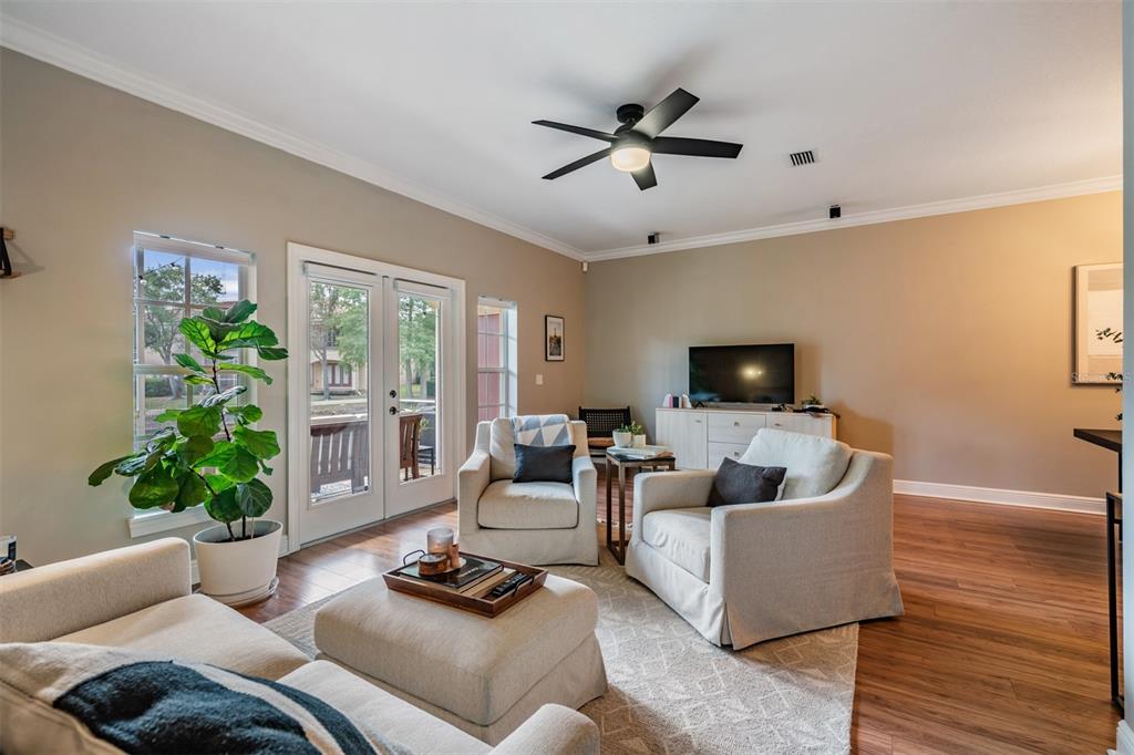 A living room features light-colored armchairs, a matching ottoman, a ceiling fan, and glass doors — 415 BARCELONA DRIVE, ST PETERSBURG, FL