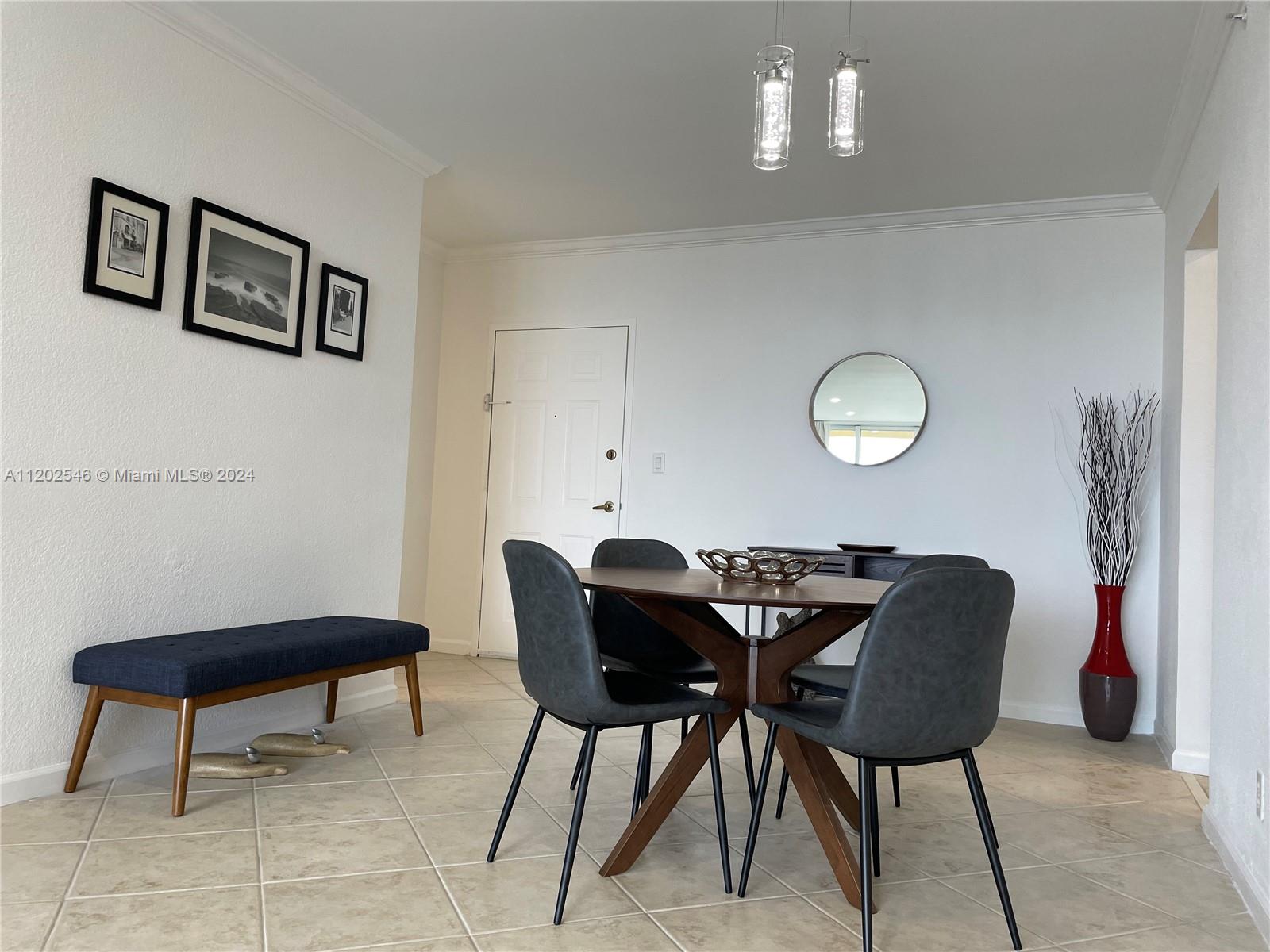 A dining area features a wooden table, four gray chairs, a bench, and wall art — 2501 S Ocean Dr, Hollywood FL 33019, HOLLYWOOD, FL