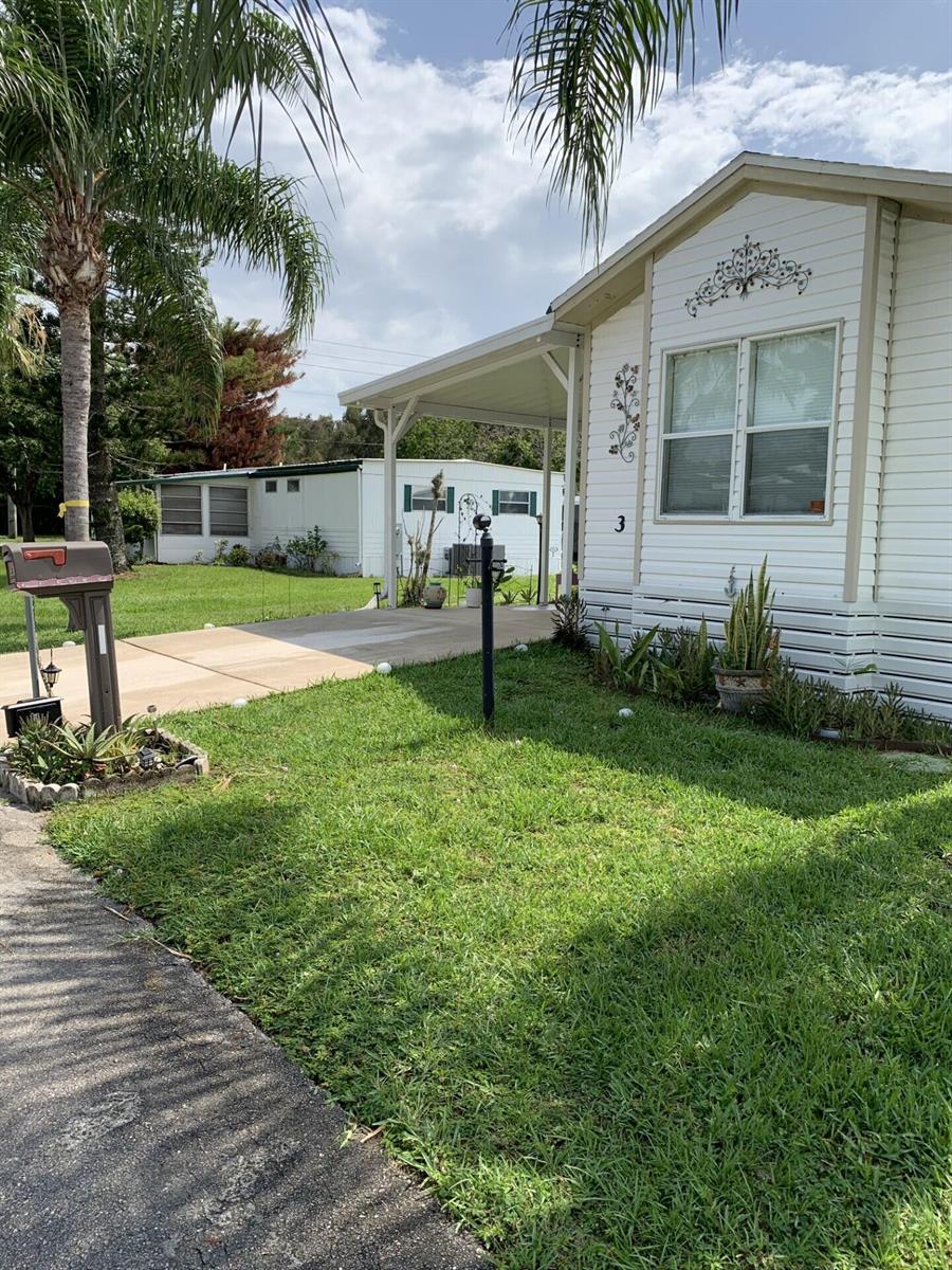 A white mobile home with a carport, a front lawn, and a mailbox — 3 Mediterranean Boulevard E, Port St. Lucie FL 34952, PORT ST. LUCIE, FL