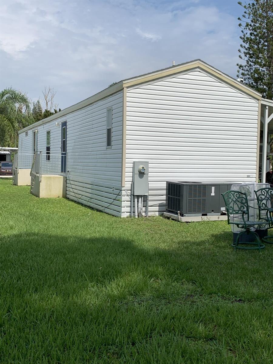The exterior side of a white vinyl-sided mobile home with an air conditioning unit — 3 Mediterranean Boulevard E, Port St. Lucie FL 34952, PORT ST. LUCIE, FL