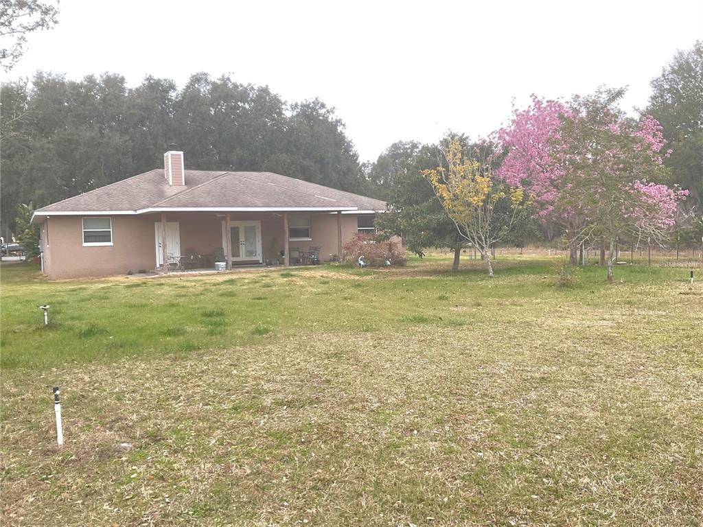 A single-story house with a covered patio sits on a large, grassy lot — 32420 COUNTY ROAD 473, LEESBURG, FL