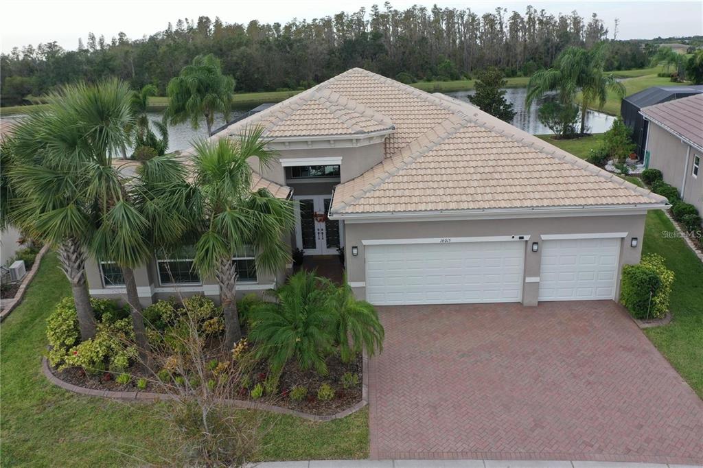 An aerial view of a single-story house with a tiled roof, garage, and palm trees — 16015 CAPE CORAL DRIVE, WIMAUMA, FL