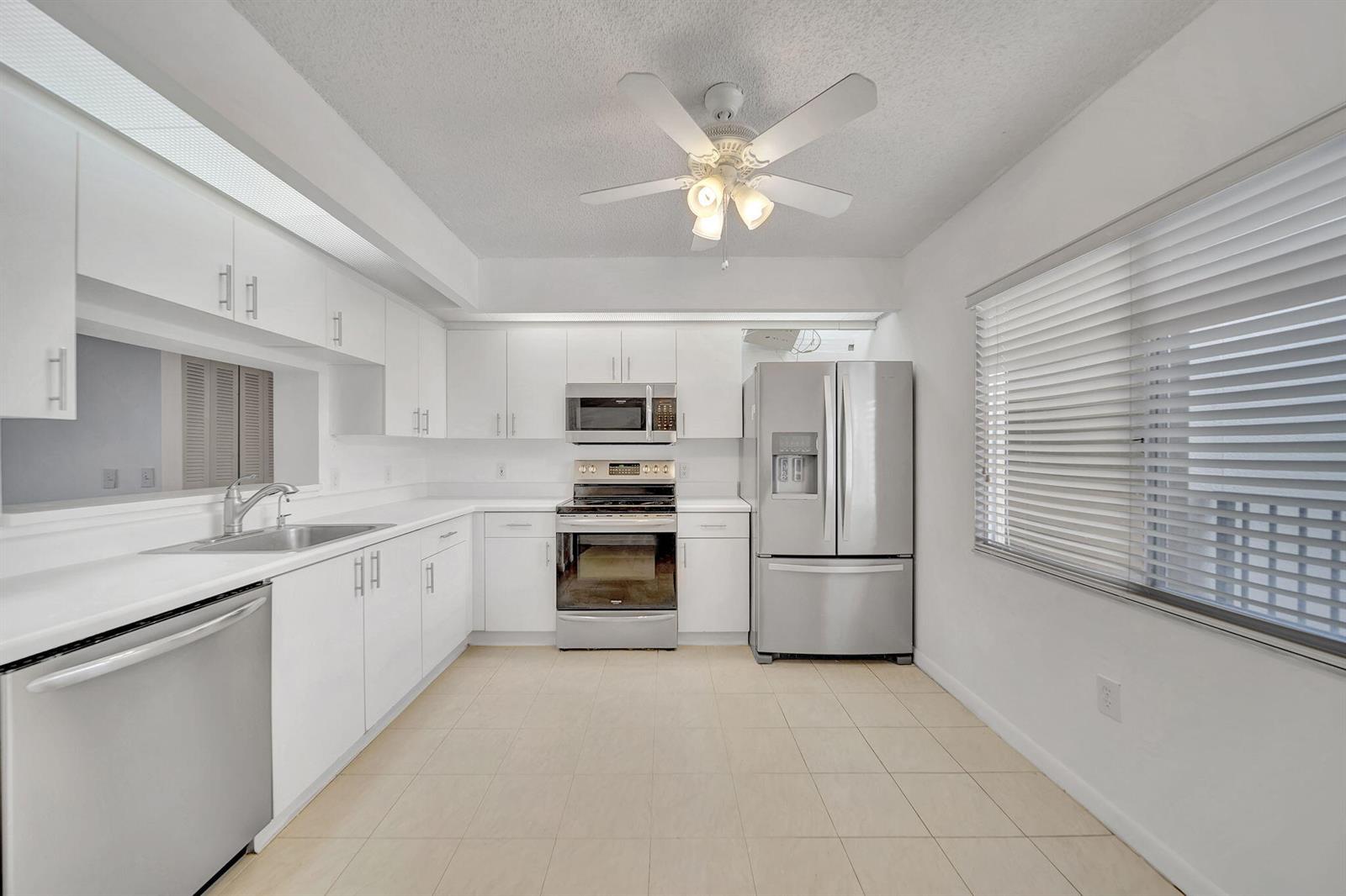A kitchen with white cabinets, stainless steel appliances, tile flooring, and a ceiling fan — 801 SW 141st Avenue # o, Pembroke Pines FL 33027, PEMBROKE PINES, FL