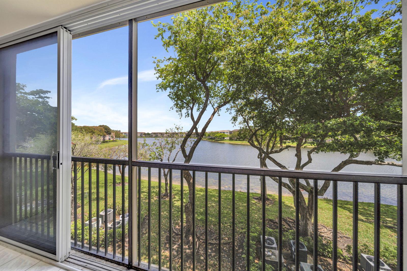 A balcony with a black metal railing overlooks a lake surrounded by green trees — 801 SW 141st Avenue # o, Pembroke Pines FL 33027, PEMBROKE PINES, FL