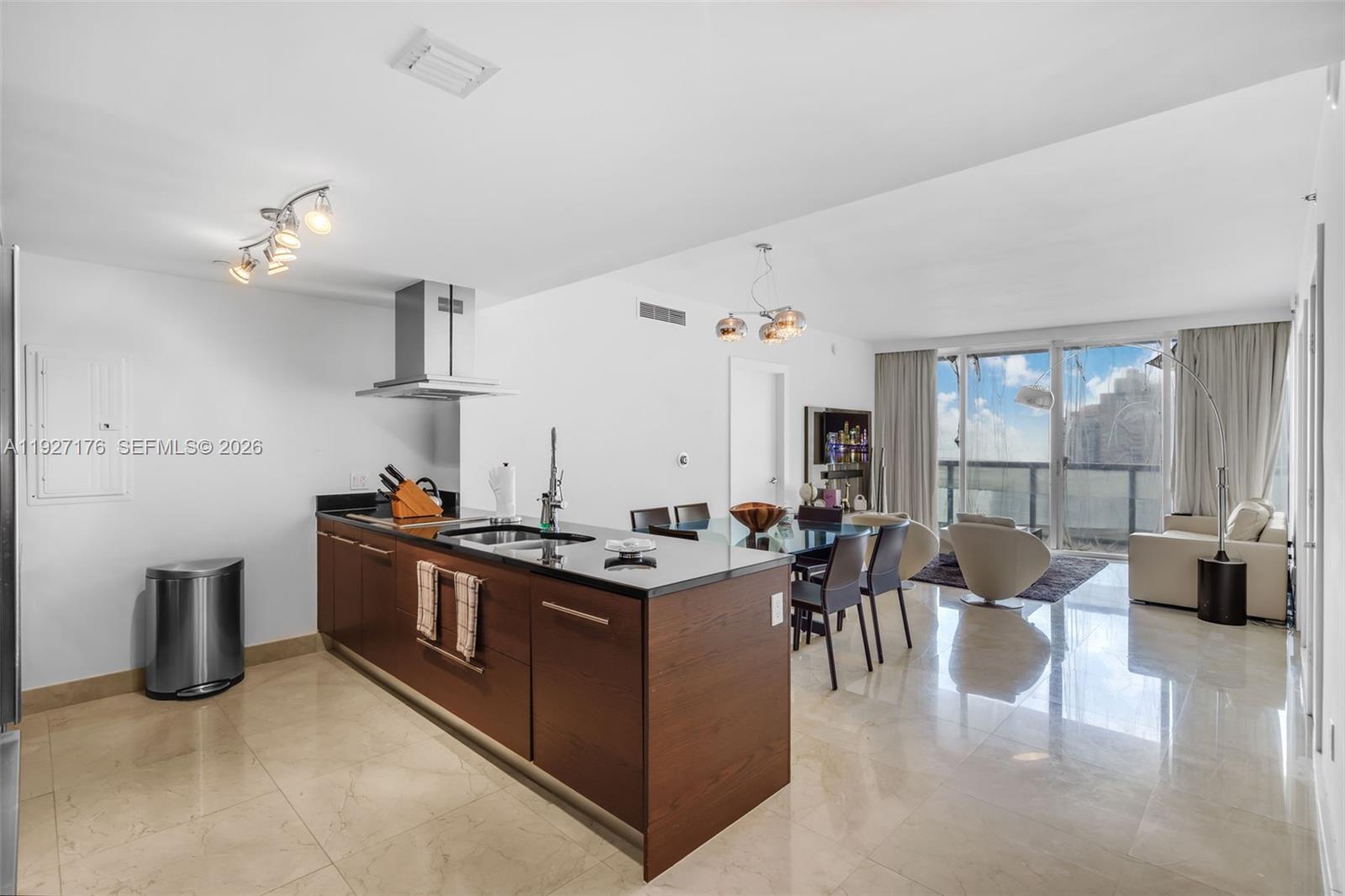 A modern kitchen with dark wood cabinets and black countertops opens into a dining area — 495 Brickell Ave # 2405, Miami FL 33131, MIAMI, FL