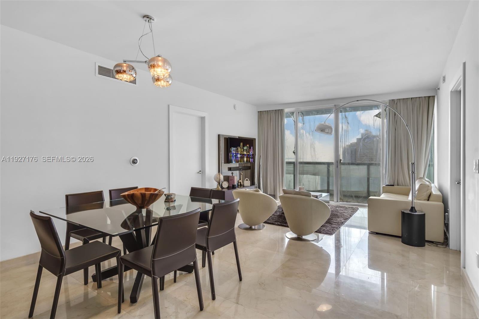 A modern living and dining area features tile floors, a glass table, and balcony views — 495 Brickell Ave # 2405, Miami FL 33131, MIAMI, FL