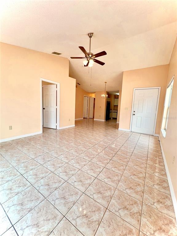 A living room with light-colored tile flooring, peach walls, and a ceiling fan — 2416 CONDADO COURT, KISSIMMEE, FL