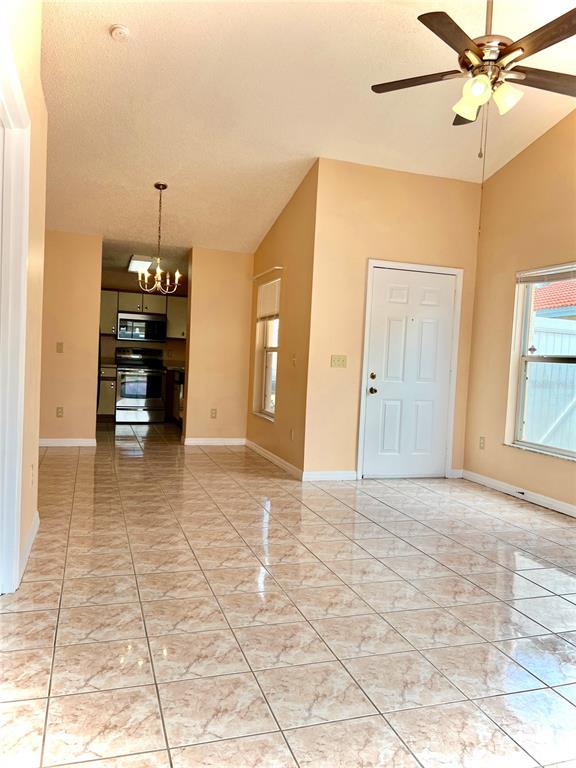 A room with light-colored tile flooring, a vaulted ceiling, a ceiling fan, and a kitchen — 2416 CONDADO COURT, KISSIMMEE, FL