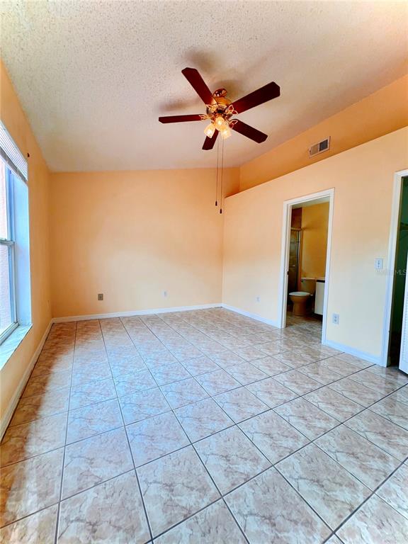 A bedroom with light orange walls, tile flooring, and a ceiling fan — 2416 CONDADO COURT, KISSIMMEE, FL