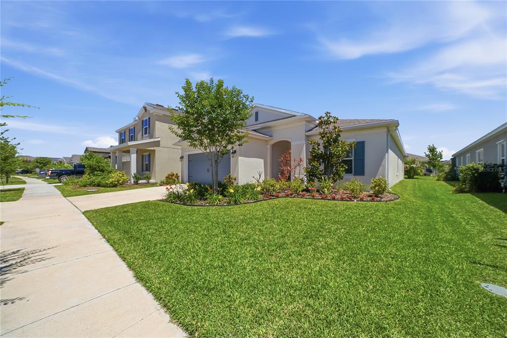A single-story suburban house with a tan exterior, a two-car garage, and a landscaped lawn — 5521 LIMELIGHT DRIVE, APOLLO BEACH, FL