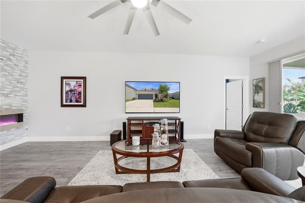 A living room features a wall-mounted television, a fireplace, and brown leather furniture — 5521 LIMELIGHT DRIVE, APOLLO BEACH, FL
