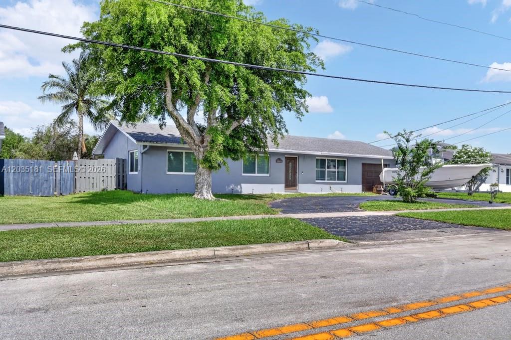 A single-story gray house with a large tree and a boat parked in the driveway — 1000 W River Dr, Margate FL 33063, MARGATE, FL
