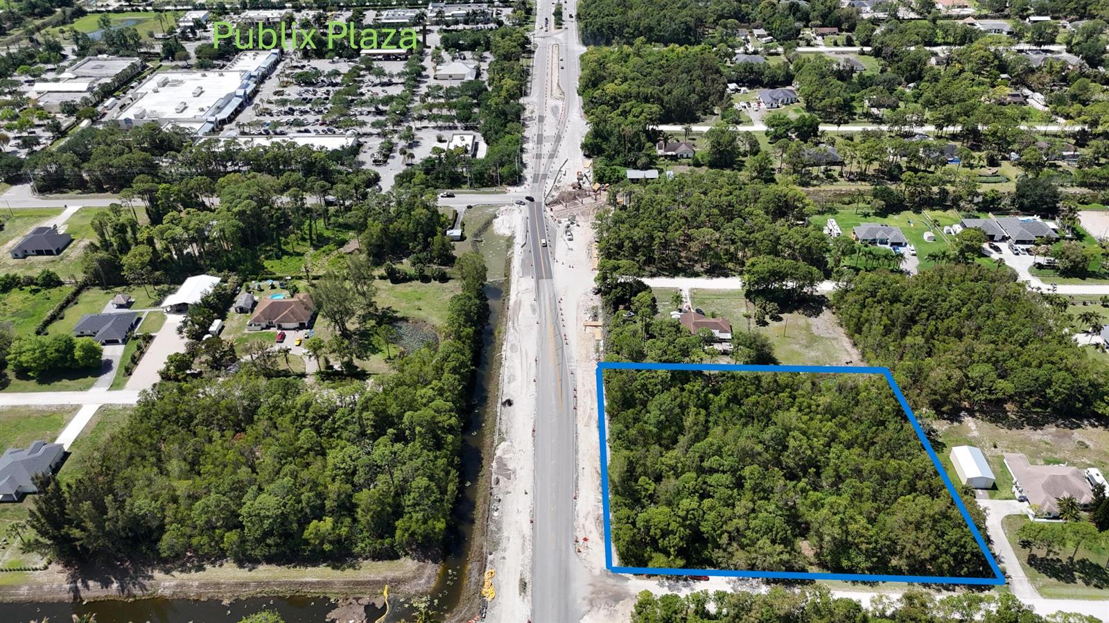 An aerial view shows a rectangular wooded lot outlined in blue next to a road — 000 73rd Court N, FL 33470, FL