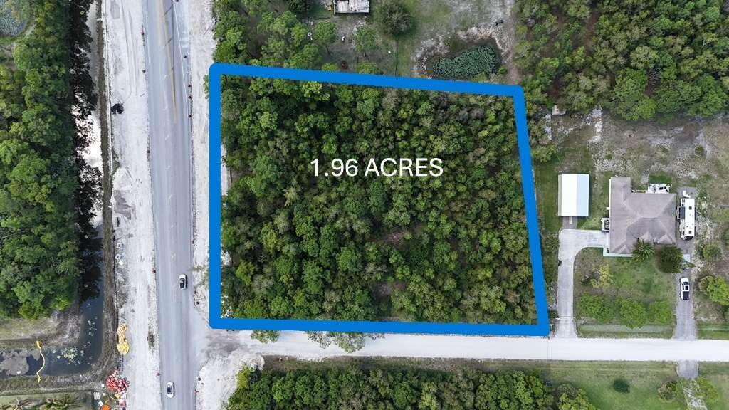 An aerial view shows a wooded 1.96-acre rectangular lot bordered by a road and houses — 000 73rd Court N, FL 33470, FL