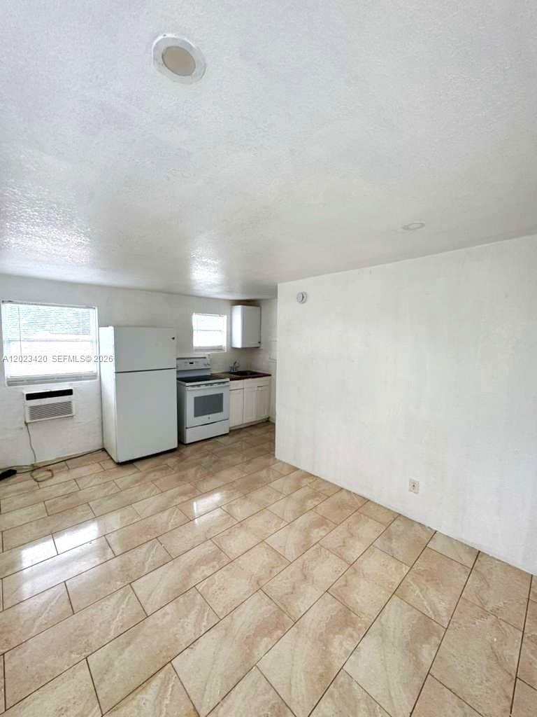 A kitchen with white appliances, light-colored tile flooring, and white walls — HOMESTEAD, FL