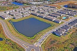 An aerial view shows a residential neighborhood featuring townhomes surrounding a large central retention pond — 8239 CRESCENT OAKS DRIVE, NEW PORT RICHEY, FL