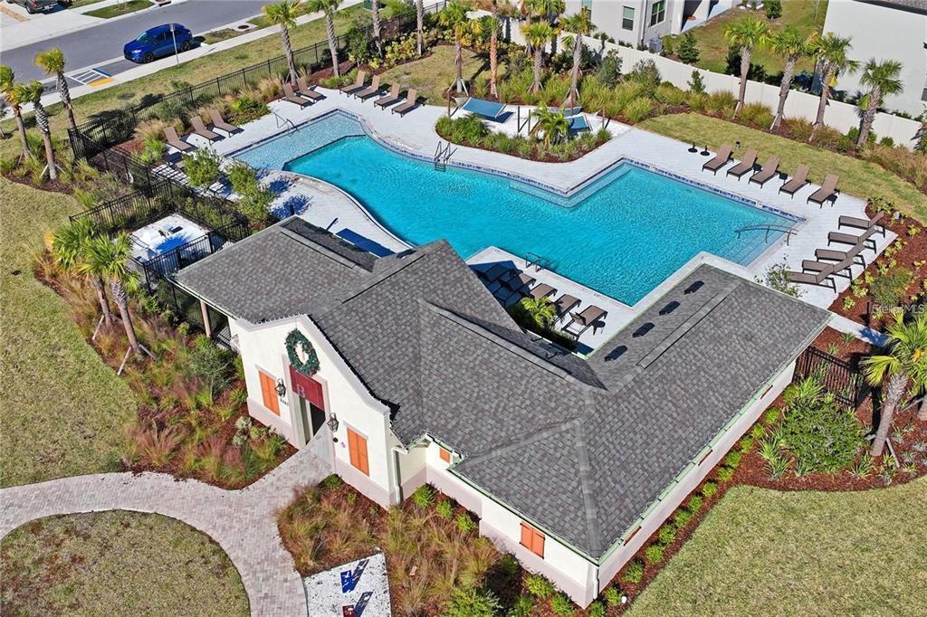An aerial view shows a community clubhouse with a large L-shaped swimming pool and patio — 8239 CRESCENT OAKS DRIVE, NEW PORT RICHEY, FL