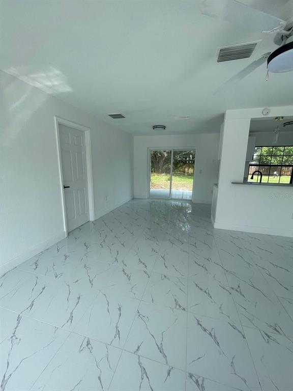A room with white marble-patterned tile flooring, a white door, and sliding glass doors — 113 TEAK LOOP, OCALA, FL