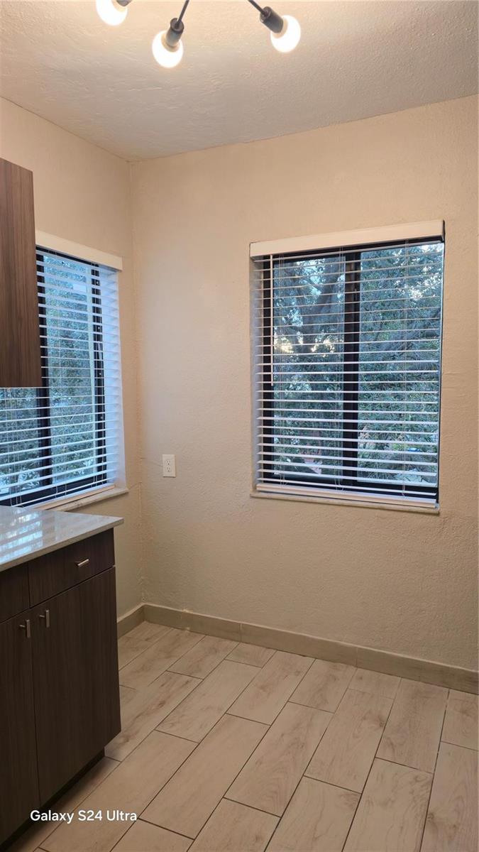A kitchen corner features wood-look tile flooring, two windows with blinds, and dark cabinetry — 360 NW 8th Street # 8, Pompano Beach FL 33060, POMPANO BEACH, FL