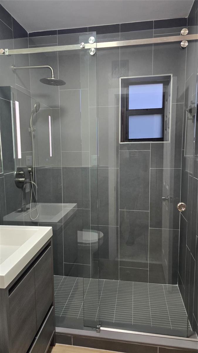 A modern bathroom features a glass-enclosed walk-in shower with gray tile and a rainfall showerhead — 360 NW 8th Street # 8, Pompano Beach FL 33060, POMPANO BEACH, FL