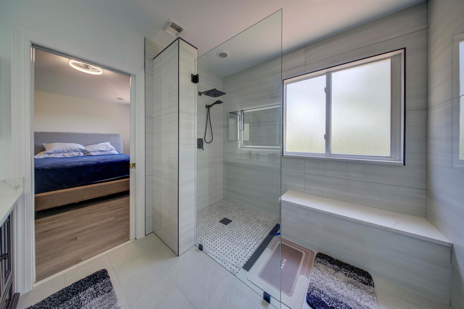 A modern bathroom features a glass-enclosed walk-in shower with a built-in bench and tiled walls — 2364 Center Stone Lane, Riviera Beach FL 33404, RIVIERA BEACH, FL