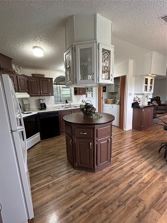 A kitchen features brown cabinets, a central island, and a hanging glass-front cabinet unit — 19449 165 LANE, O'BRIEN, FL