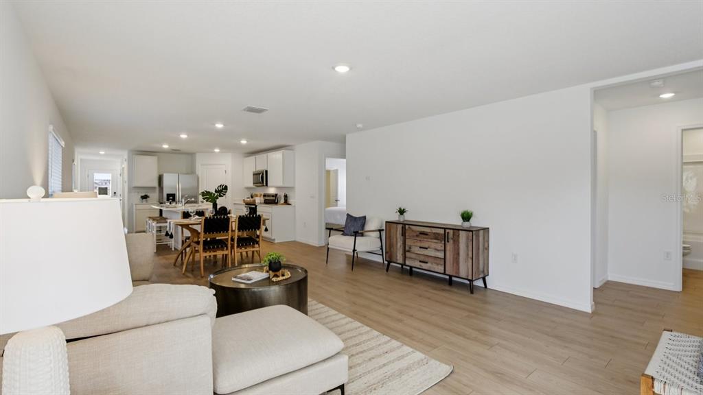 An open-concept living room features light wood flooring, a dining area, and a modern kitchen — 432 WARM HERON PLACE, RUSKIN, FL