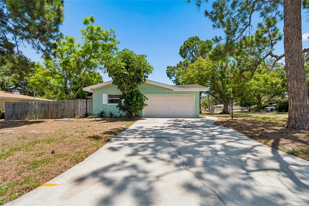 A light green single-story house with a two-car garage and a concrete driveway — 1357 S EVERGREEN AVENUE, CLEARWATER, FL