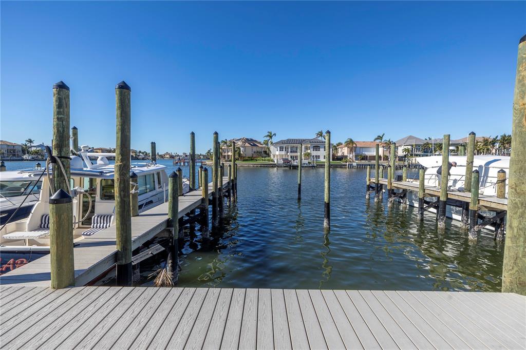 A wooden dock overlooks a canal with moored boats and waterfront houses under a clear sky — 2795 KIPPS COLONY DRIVE S UNIT 305, ST PETERSBURG, FL