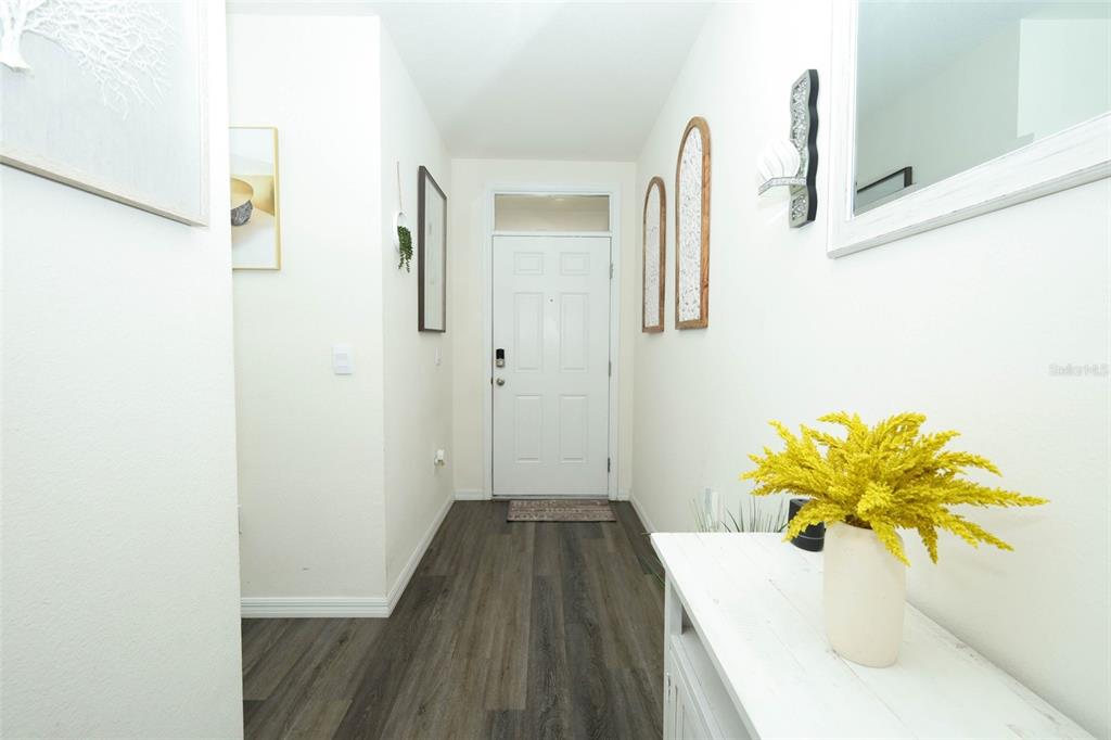 A bright entryway features wood-look flooring, a white front door, and a decorative console table — 6310 CANTER CIRCLE, APOPKA, FL