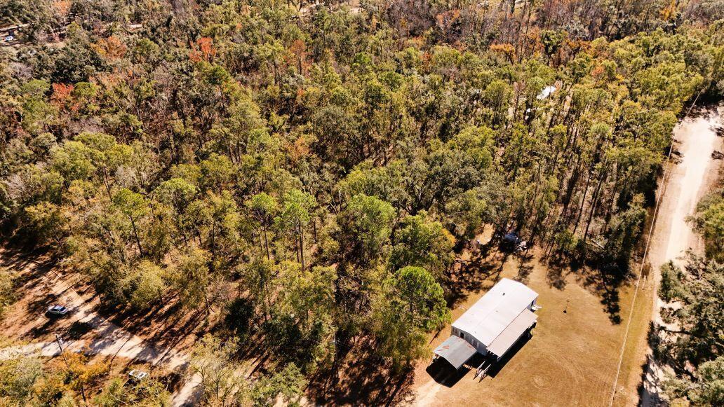 An aerial view shows a house with a metal roof situated beside a wooded area — Lot 26 NW White Oak Way, FL 32053, FL