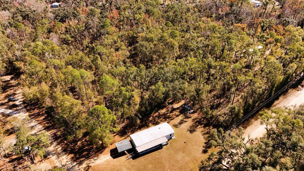 An aerial view shows a single-story home situated on a large, wooded lot — Lot 26 NW White Oak Way, FL 32053, FL