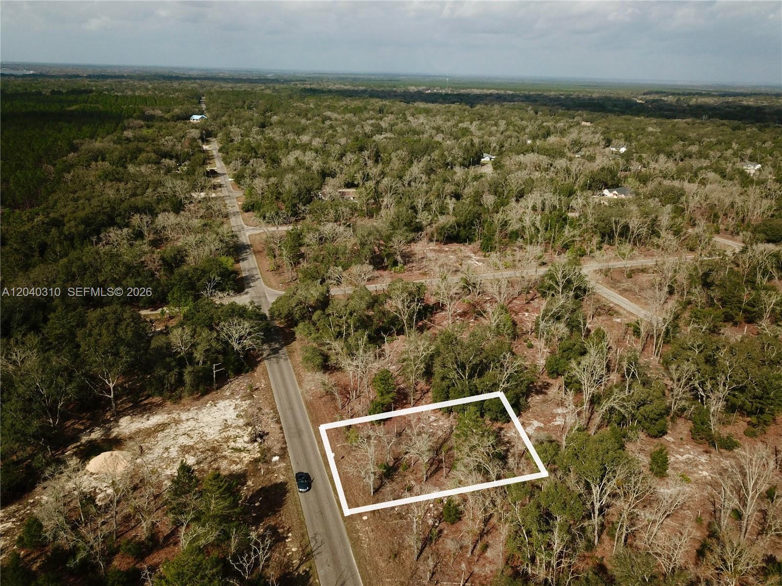 An aerial view shows a rectangular plot of land outlined in white beside a road — Lot Nearby 19 Bay Track Court, Other City - In The State Of Florida FL 32179, OTHER CITY - IN THE STATE OF FLORIDA, FL