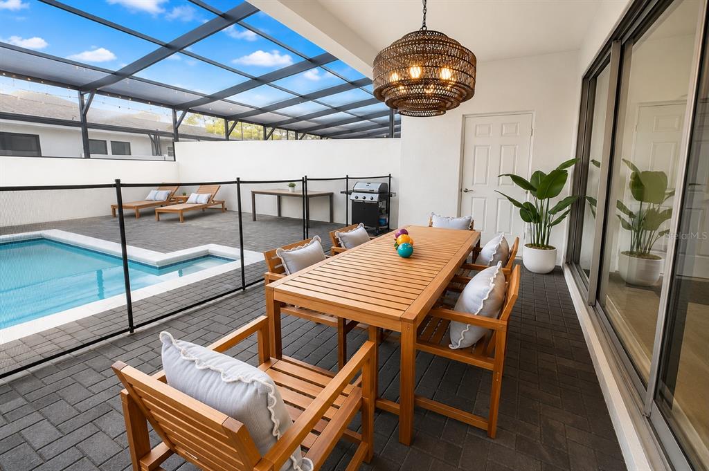 A covered patio features a dining set, a swimming pool, and a black metal fence — 2441 DUBAI STREET, KISSIMMEE, FL