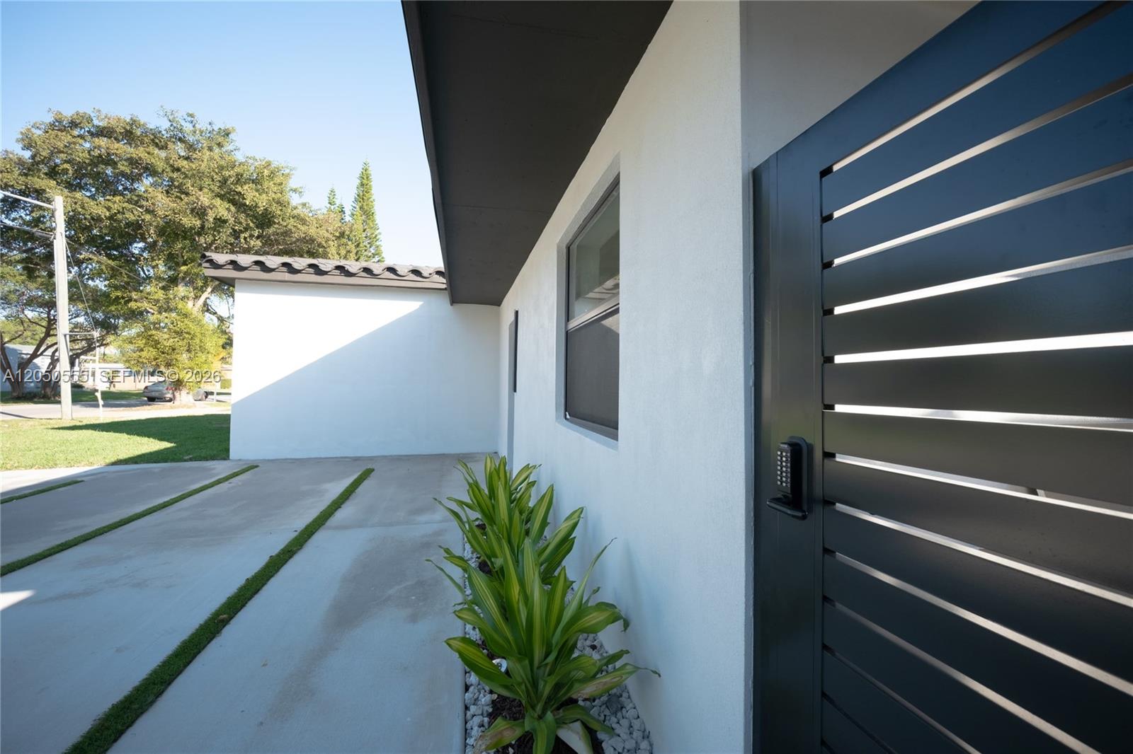 A modern white exterior wall features a slatted gate with a digital keypad — 15411 NE 10th Ave, North Miami Beach FL 33162, NORTH MIAMI BEACH, FL
