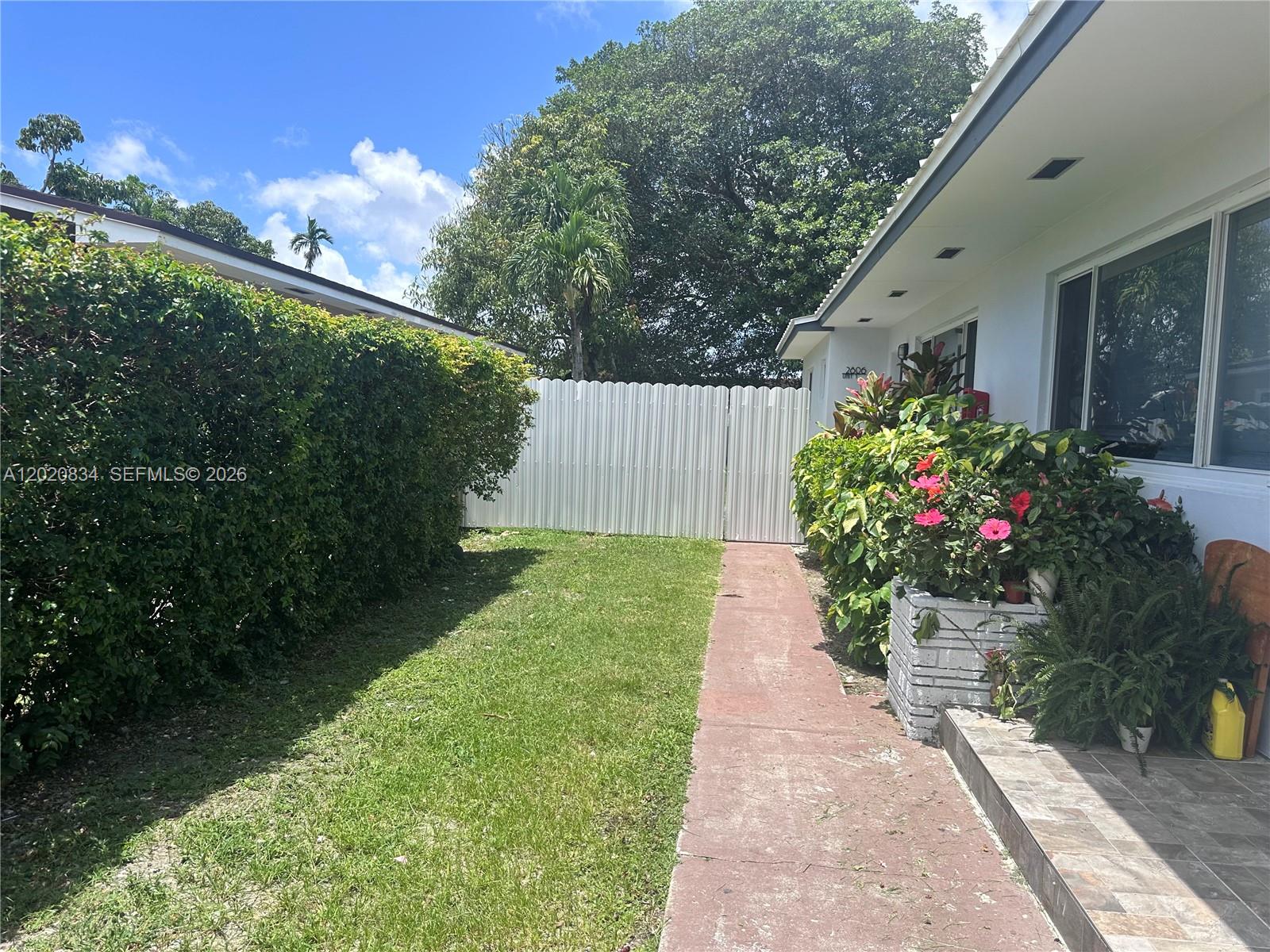 A white house exterior features a red walkway, a green hedge, and a metal fence — 2806 SW 35th Ave # 1, Miami FL 33133, MIAMI, FL